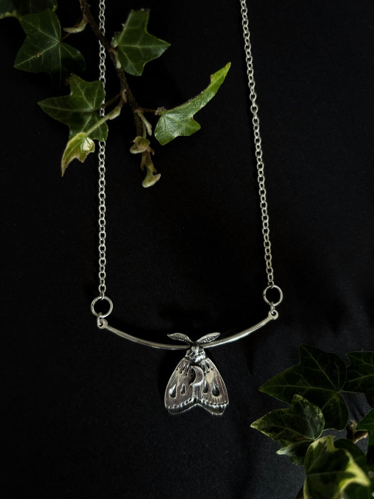 silver moth pendant on black background. Handcrafted silver moth pendant with detailed wings, inspired by nocturnal nature and made in Ireland by Irish jewellery designer